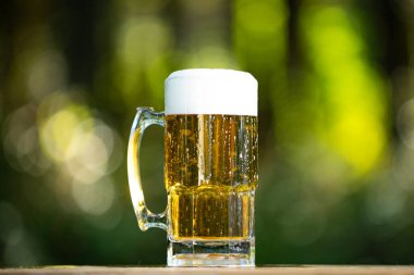 Yeşil Bokeh arka planında cam bira. Köpüklü bira yakın çekim. Bira bardağı yaz rahatlaması. El yapımı biranın tadı. Bira bardağı.