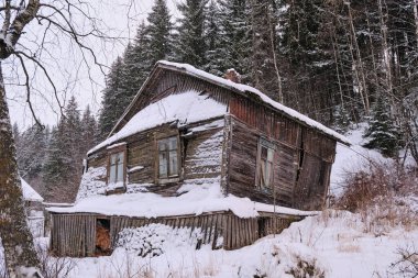 Çürük ahşap bir bungalovun arka planında karla kaplı. Eski ev. Sortavala, Karelia.