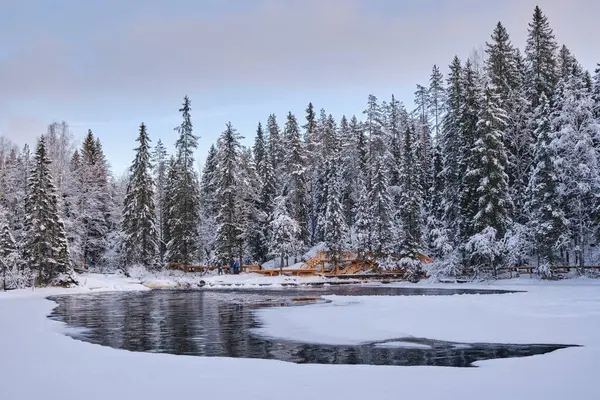 Tohmajoki Nehri 'nin buzu üzerindeki buzlar, Akhvenkoski şelalesi yakınlarındaki güzel bir kış ladin ormanının arka planına karşı eridi. Ruskeala, Karelia.
