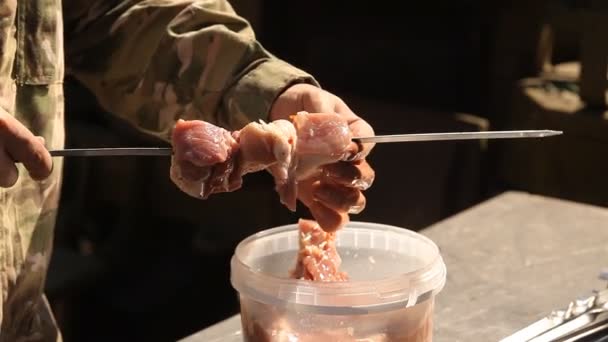 Чоловік нанизує м'ясо на шампур — стокове відео