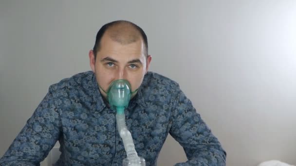 Un hombre tomando inhalación. Use un nebulizador e inhalador para el tratamiento. La persona enferma inhala a través de la máscara del inhalador. Periodo de cuarentena, tratamiento de enfermedades respiratorias — Vídeos de Stock