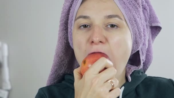 Portret młodej pięknej kobiety po prysznicu jedzącej duże jabłko, odgryzającej kawałki. Koncepcja wegetarianizmu, świeże owoce w rękach młodej dziewczyny, zdrowe odżywianie — Wideo stockowe