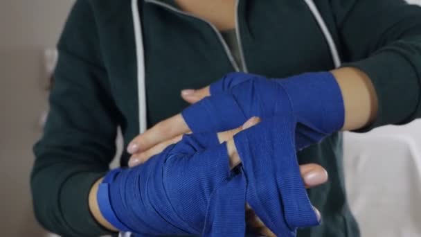 Een vrouw in haar armen, gewikkeld in bokslinten, bereidt zich voor op een training in de sportschool. Vrouw bedekt haar handen met professionele boksbanden — Stockvideo