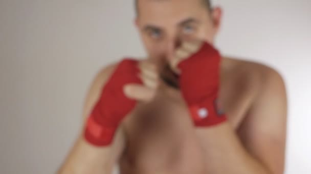 Łysy mężczyzna z bandażem na rękach wykonuje ćwiczenia i różne ruchy bokserskie. Jaki sport lubisz najbardziej? — Wideo stockowe