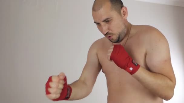 Лисий чоловік з огидним животом з пов'язкою на руках виконує вправи і різні боксерські рухи, намагаючись стати відомим боксером — стокове відео
