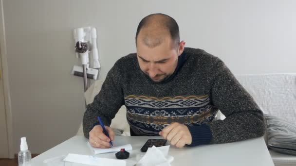 Hombre sentado en la sala de estar haciendo análisis financiero, sosteniendo recibo de ventas, montón de recibos, preocupado por la escasez de dinero, problemas financieros de bancarrota de pequeñas empresas, concepto de gasto excesivo — Vídeos de Stock