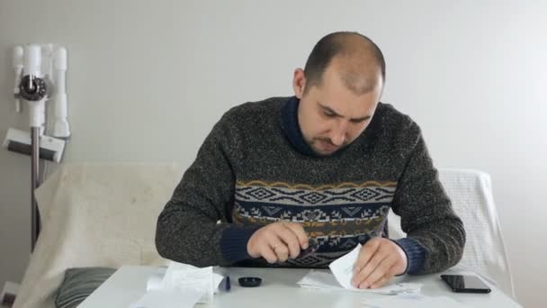 A man sits in the living room in his house during the coronavirus on self-isolation and makes a financial analysis of his business, puts seals, stamps on receipts, financial problems — Stock Video