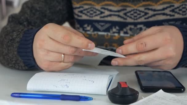 Člověk používá kalkulačky a dokumenty, které počítají výdaje v domácí kanceláři
