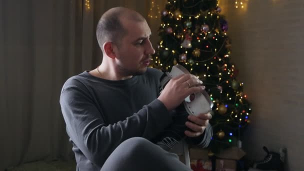 Fiatal ember közel karácsonyfa korcsolyával a kezében — Stock videók