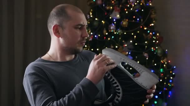 Junger Mann mit Schlittschuhen in der Hand am Weihnachtsbaum — Stockvideo