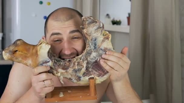 L'uomo calvo è disgustoso, rosicchiando il prosciutto serrano spagnolo sull'osso nel suo appartamento.Jamon — Video Stock