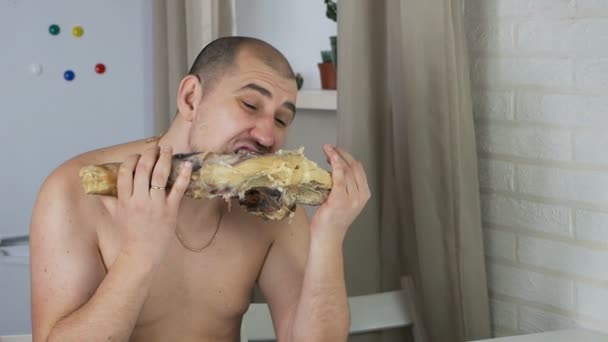 Ten plešatý muž je nechutný, okusuje španělskou serrano šunku na kost ve svém bytě. Jamon — Stock video