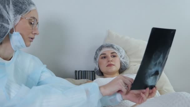 Doktor se dívá na výsledky počítačové tomografie pacienta ležícího na lůžku na pohotovosti a diskutuje o nich — Stock video
