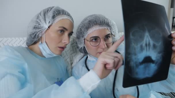 Twee artsen onderzoeken een patiënt X-stralen voor een diagnose tijdens een theepauze — Stockvideo