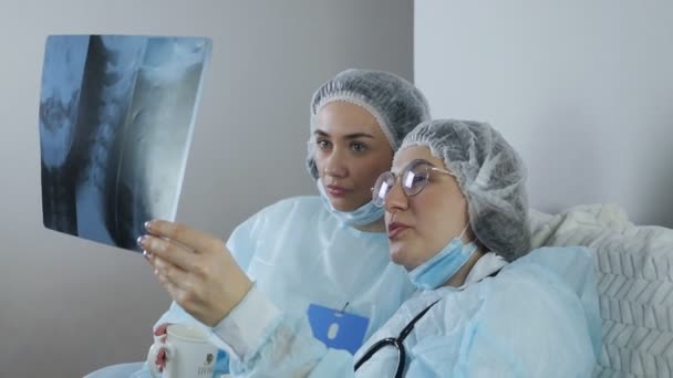 Два врача осматривают пациентов на рентгеновские снимки для диагностики во время перерыва — стоковое видео