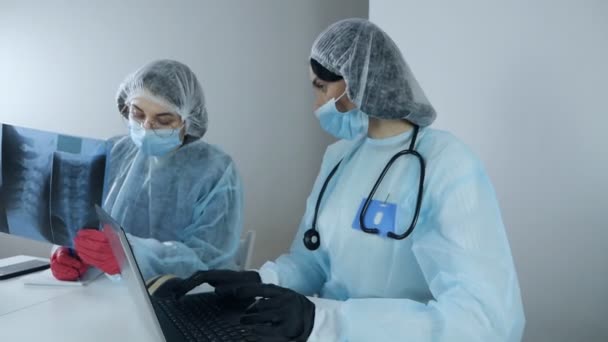 Young women professional laboratory scientist specialists working in modern clinical laboratory discussing medical research results by typing on laptop — Stock Video