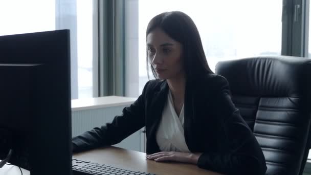 Mladá brunetka na pracovišti v kanceláři u okna, pracuje na počítači. Obchod — Stock video
