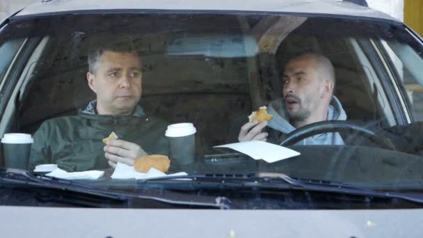 Male private detectives are sitting in the car, eating donuts and conducting surveillance. Spy, surveillance, crime — Stock Video