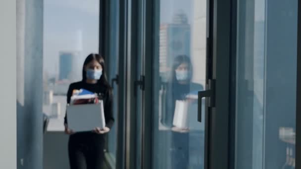 Jeune femme à la fenêtre dans le bureau, perd son emploi, tenant ses effets personnels dans une boîte, quittant son emploi, licenciée à cause de la crise. — Video