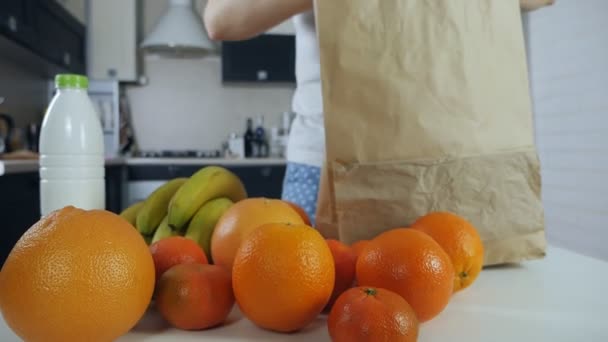 La chica desempaca una bolsa de papel con frutas en la cocina después de comprar — Vídeos de Stock