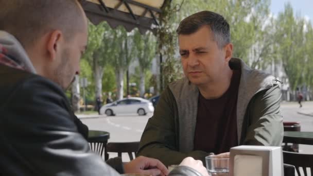 Two men in a summer cafe talking and enjoying their time — Stock Video