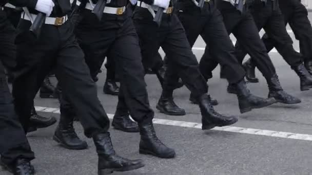 De marcherende benen van een groep mannen in blauwe uniformen tijdens een middagparade op straat. — Stockvideo