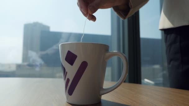 Zanurz torebkę herbaty w gorącej wodzie w ceramicznym kubku, oświetlonym naturalnym porannym światłem z okna — Wideo stockowe