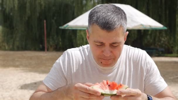 O homem está a comer uma melancia suculenta. Verão quente, delicioso fruits.low movimento — Vídeo de Stock