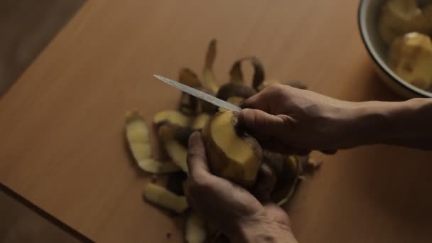 Een man reinigt de aardappelen in de keuken — Stockvideo