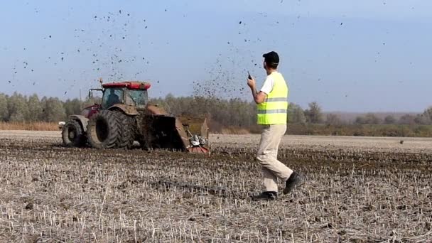 Tractor puxa uma máquina que corta os canais no campo — Vídeo de Stock