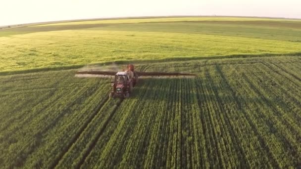 Trator puxando uma máquina de pulverização em campos de trigo — Vídeo de Stock