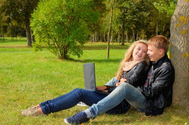 Genç çift parkta bir dizüstü bilgisayar ile eğitim