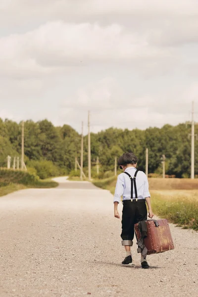 Young boy walking away with suitcase — Stock Photo, Image