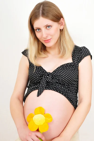 Hermosa mujer embarazada con flor de juguete — Foto de Stock