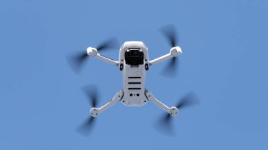 Gökyüzü mavisi arka planda uçan uzaktan kumandalı küçük bir dron ve kopyalama uzayı. İHA uçurmayı öğrenmek