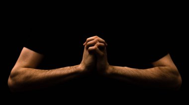 Tanrı 'ya dua eden adam siyah arka planda izole edilmiş. Din ve inanç kavramına kapalı eller