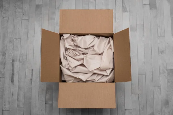 Open cardboard box filled with paper packaging. Online order shipping and unboxing a new delivery from the mail. Transportation and consumer E-commerce concept