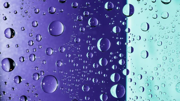 Colorful macro water droplets on a clear glass window close up. Abstract purple crescent patterns and turquoise background. Dew drop reflections in liquid wallpaper