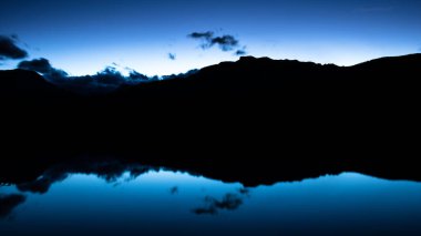 Rocky Dağı Gölü mavi saat yansıması doğa arka planı ve kopyalama alanı. Alacakaranlıktaki dağ silueti ayna duvar kağıdını yansıtıyor.
