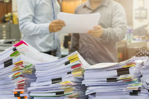 Pile of unfinished documents on office desk with businessman background — Stock Photo, Image
