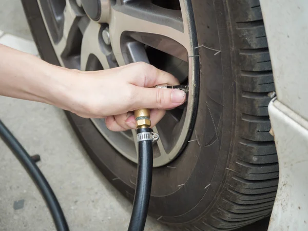 Homem de close-up verificando a pressão do ar e enchimento de ar no pneu — Fotografia de Stock
