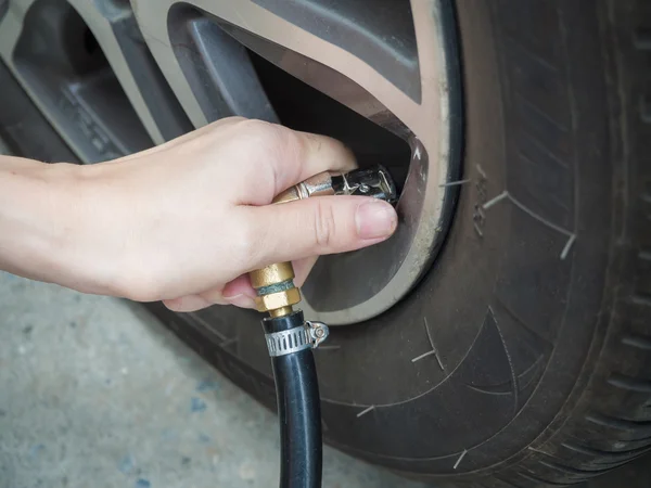 Homem de close-up verificando a pressão do ar e enchimento de ar no pneu — Fotografia de Stock