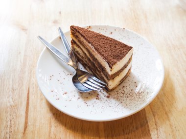 Tiramisu pasta kaşık ve çatalı ahşap masa ile seramik plaka üzerinde