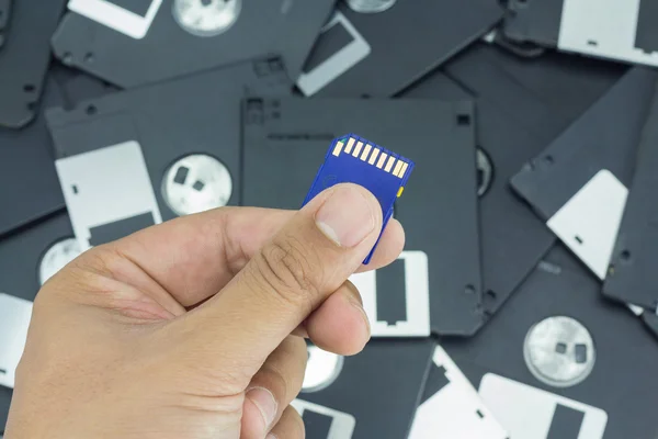 Ruka držící Sd kartu s pozadím diskety — Stock fotografie