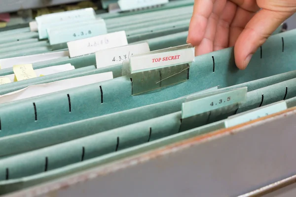Mão segurando arquivo secreto superior no armário de arquivo — Fotografia de Stock