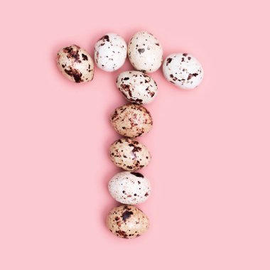 Paskalya bıldırcın yumurtalarının T harfi pembe renkli. Çikolata ile bahar paskalya kompozisyonu. Tek renkli resim