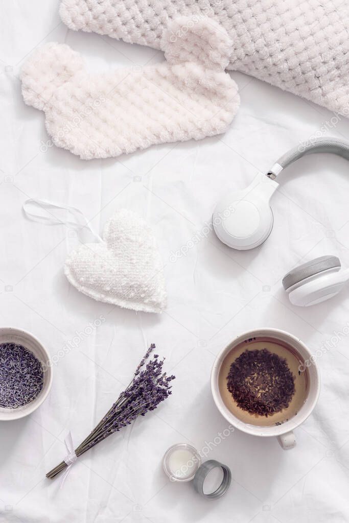 Flat lay with healthy herbal lavender tea in cup for relaxation before bedtime. Sleep mask and balsam with essential oil