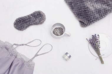Sağlıklı uyku konsepti, pijama, uyku maskesi, bir fincan lavanta çayı, daha iyi uykuya dalmak için aromalar, yastık.