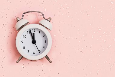 Beyaz alarmlı saat, arka planda, üzerinde kopya alanı olan pullarla kaplı yaklaşık 12 kilit gösteriyor. Yeni yıl konsepti. Düz yatıyordu. Üst görünüm.