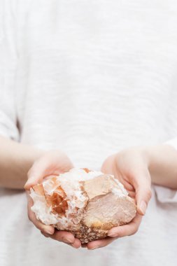 Kadın elinde ışık tutarak koruma kristali tutuyor. Doğal mineral kaya örneği, büyük güzel taş..